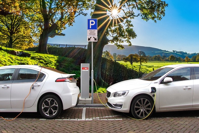 Photo of two electric vehicles plugged up to a charging station